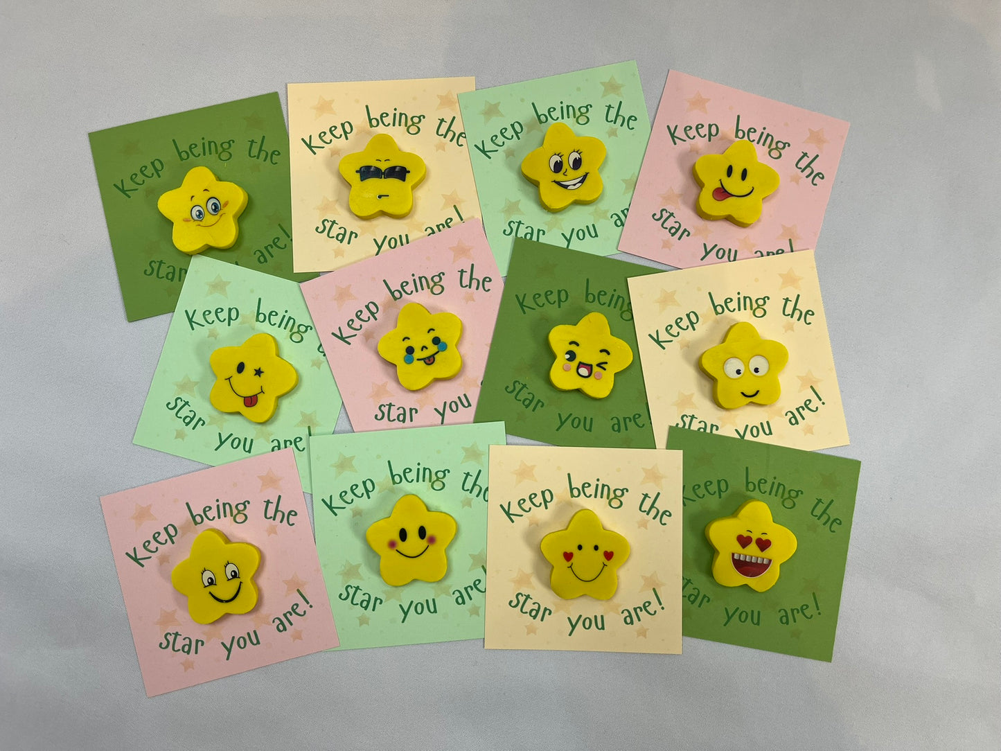 Lots of yellow rubbers in star shapes are on coloured card backings. The card reads “keep being the star you are”, they’re green, peach, pink and dark green. The stars all have different emoji style faces on, smiley, sunglasses, cheeky, heart eyes and many more.