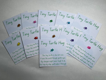 A small plastic turtle is stuck to a piece of card, with waves in the background. The card is titled “tiny turtle hug” and has a poem underneath about big changes. There are a number of cards, all with different colour turtles – gold, pink, green, blue, purple, yellow, red.
