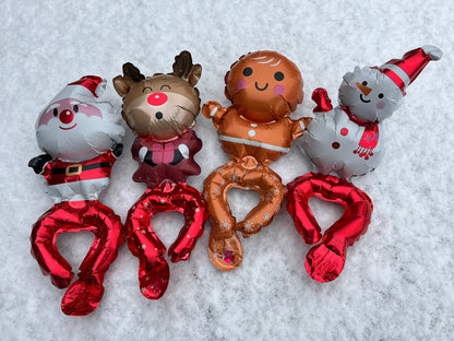 Four balloon bracelets sit in the snow, Santa, a reindeer, gingerbread man and a snowman.