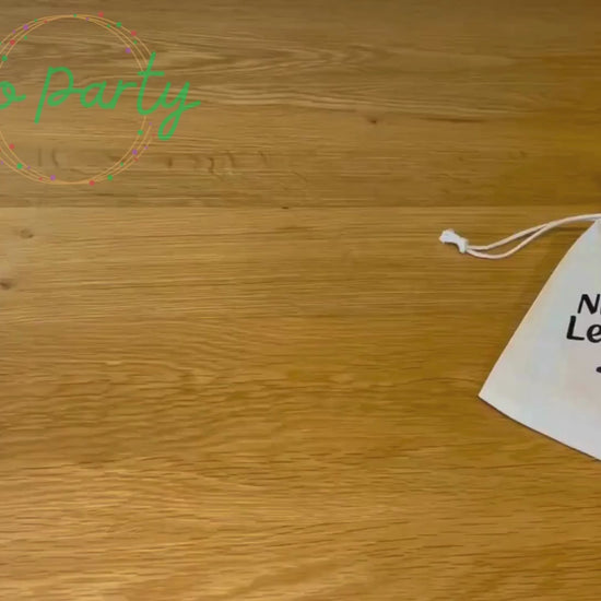 An unboxing video of the Nursery Leavers 2025 bag: there is a glowstick wands with a star on top, a blue pencil on a card saying dream big, a white envelope labelled forget-me-not seeds, a wooden circular medal that has a graduation cap and I graduated 2025 on it, a red class of 2025 wristband, and a yellow smiley star rubber on a card reading keep being the star you are. They are all laid out on a wooden surface. 