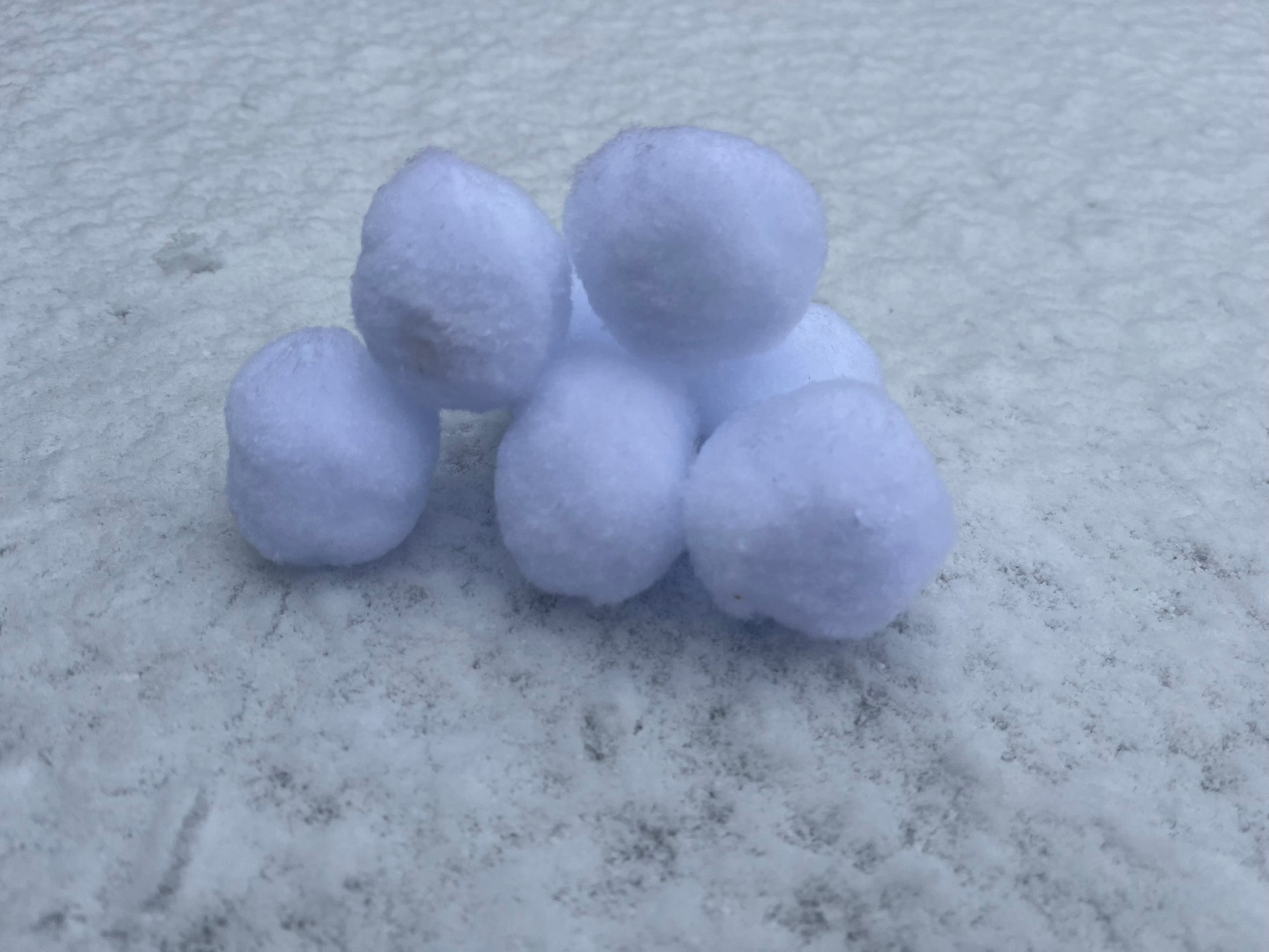 A stack of fluffy snowballs sit upon real snow.